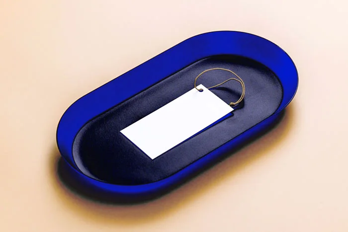 Photo showing a white label on a tray. The label is blank, white, and has a cord attached for tying. 